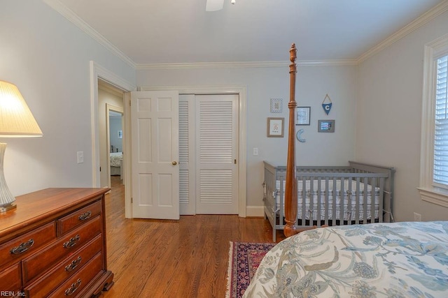 bedroom with light wood-style floors, crown molding, and a closet