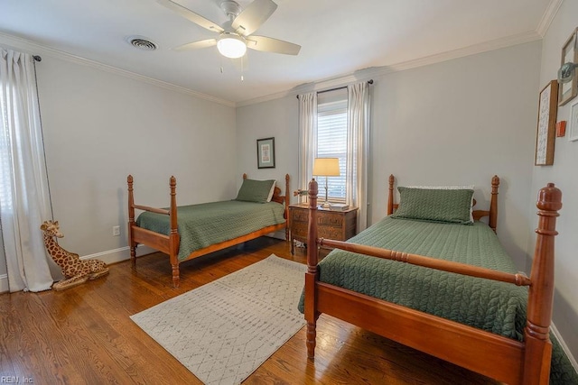 bedroom featuring wood finished floors, a ceiling fan, baseboards, visible vents, and crown molding