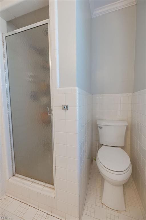 bathroom with ornamental molding, a stall shower, toilet, and tile walls