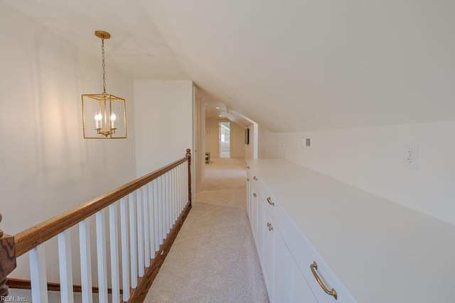 hallway with vaulted ceiling and light colored carpet