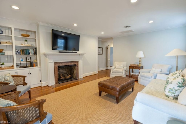 living area featuring recessed lighting, crown molding, a premium fireplace, and wood finished floors