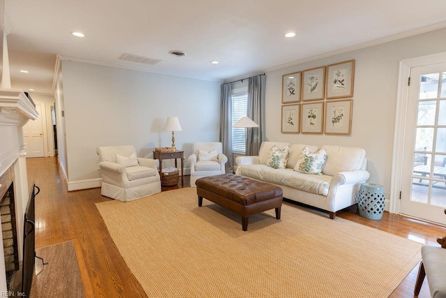 living room with ornamental molding, visible vents, a fireplace, and wood finished floors