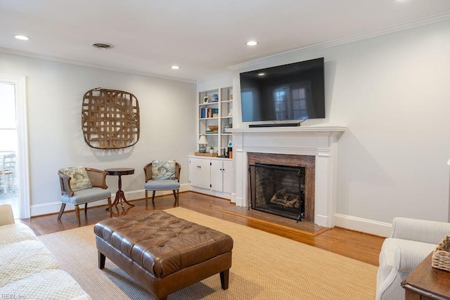 living area featuring visible vents, crown molding, and wood finished floors