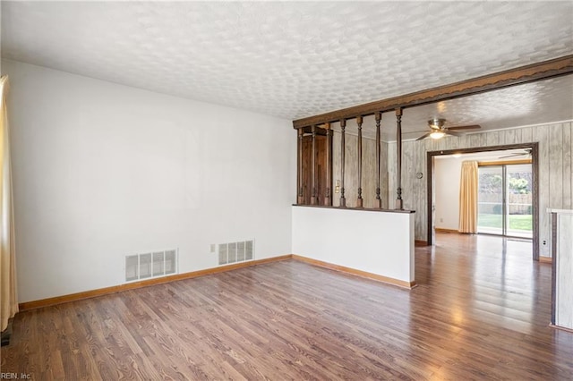 spare room with visible vents, baseboards, a textured ceiling, and wood finished floors