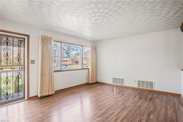 spare room featuring visible vents, a textured ceiling, and wood finished floors