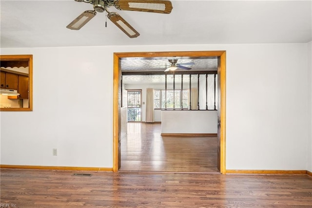 empty room with ceiling fan, baseboards, and wood finished floors