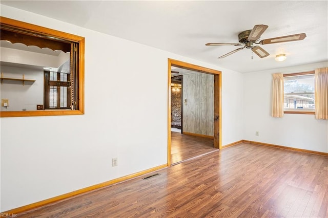 spare room with visible vents, ceiling fan, baseboards, and wood finished floors