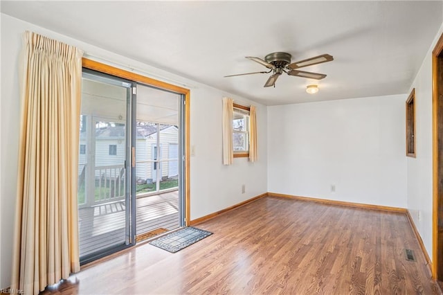 unfurnished room with a ceiling fan, visible vents, wood finished floors, and baseboards