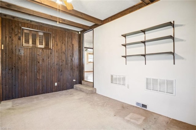 empty room with visible vents, wooden walls, and carpet floors