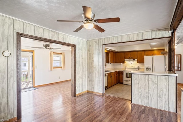 kitchen with under cabinet range hood, light wood-type flooring, light countertops, white appliances, and a sink