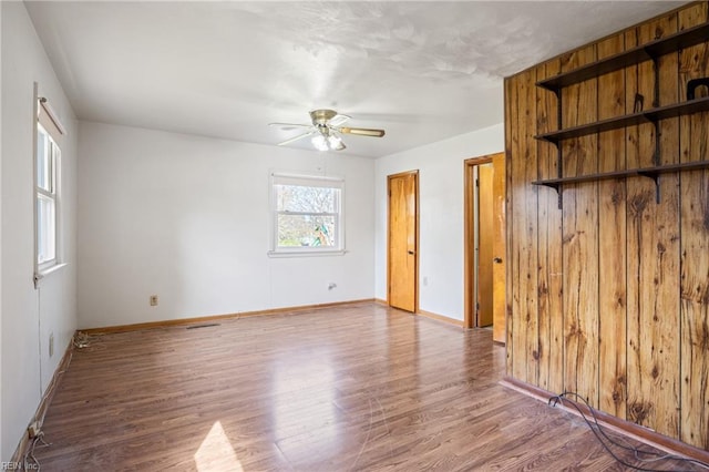 unfurnished room with a ceiling fan, baseboards, and wood finished floors