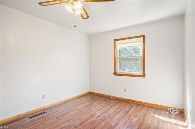 spare room featuring ceiling fan, wood finished floors, visible vents, and baseboards