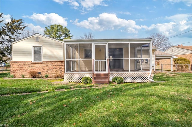 back of property featuring fence, a sunroom, crawl space, a lawn, and brick siding