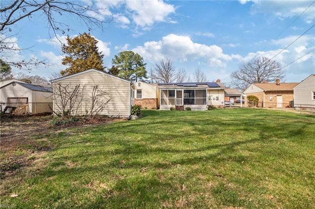 back of house featuring a lawn, solar panels, fence, and a sunroom