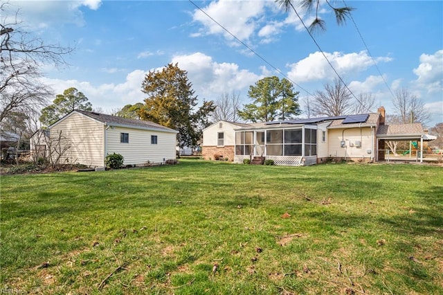 rear view of house with solar panels, a yard, and a sunroom