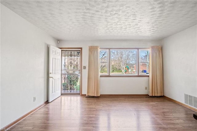 spare room featuring visible vents, baseboards, and wood finished floors