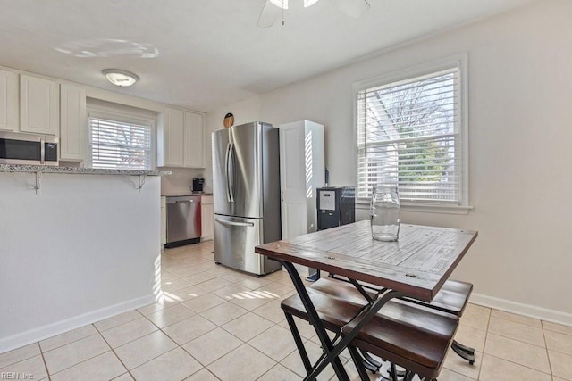 kitchen featuring stainless steel appliances, a wealth of natural light, light tile patterned flooring, and white cabinetry