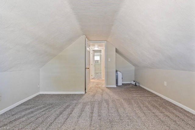 additional living space featuring carpet floors, lofted ceiling, a textured ceiling, and baseboards