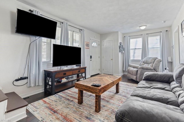 living room featuring a healthy amount of sunlight, baseboards, visible vents, and wood finished floors