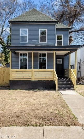 american foursquare style home featuring covered porch and fence