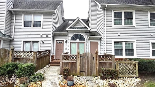 view of front of property with french doors, roof with shingles, fence, and a gate