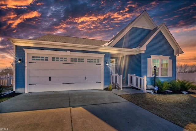 view of front facade with concrete driveway, an attached garage, and fence