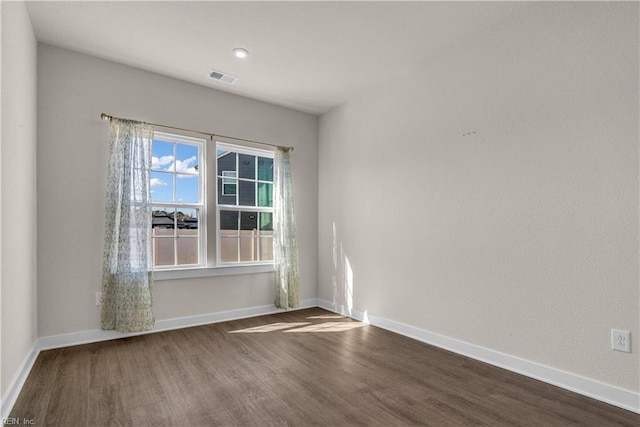 unfurnished room featuring dark wood finished floors, visible vents, and baseboards