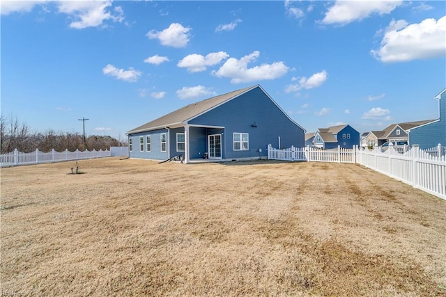 back of property with a fenced backyard and a yard