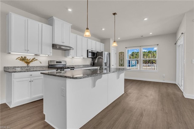 kitchen with a kitchen island with sink, under cabinet range hood, stainless steel appliances, a sink, and white cabinets