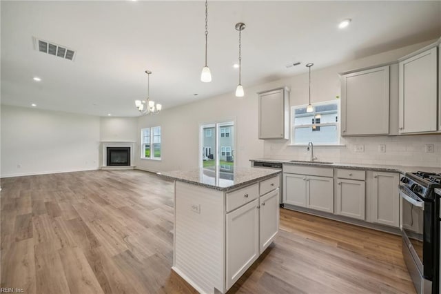 kitchen featuring gas range, tasteful backsplash, visible vents, and a sink