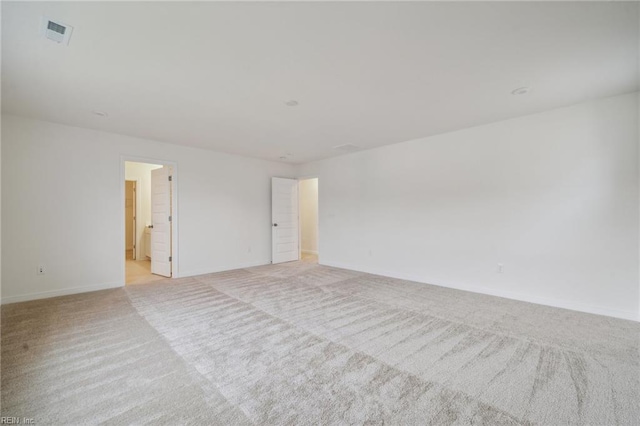 unfurnished room featuring baseboards, visible vents, and light colored carpet