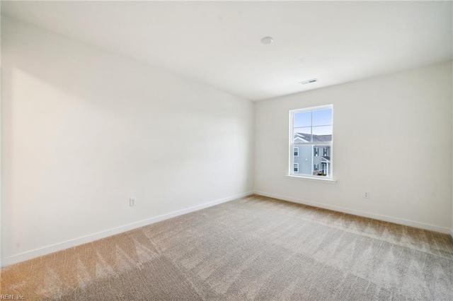 spare room featuring carpet, visible vents, and baseboards