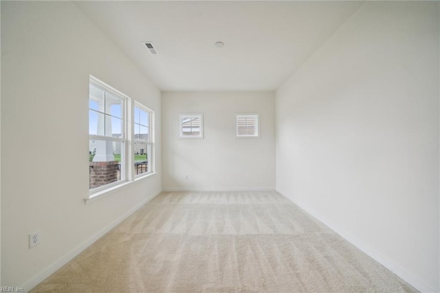 spare room featuring carpet floors, visible vents, and baseboards