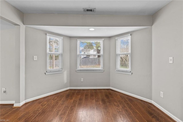 unfurnished room featuring baseboards, visible vents, and wood-type flooring