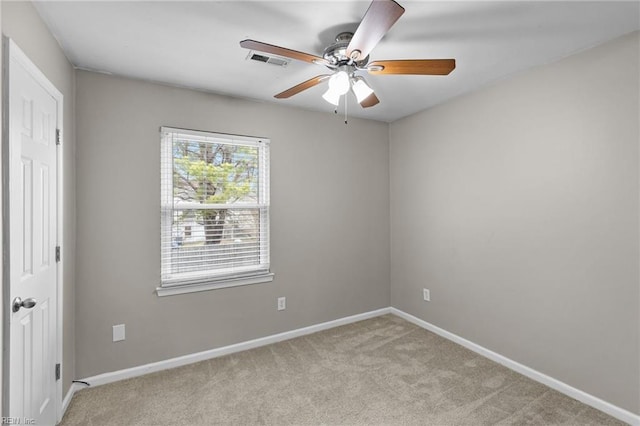 spare room with visible vents, light colored carpet, baseboards, and ceiling fan