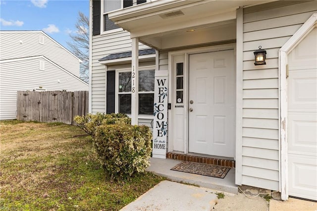 entrance to property with a lawn and fence