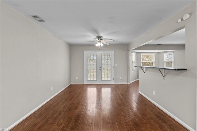 unfurnished living room with dark wood-style floors, visible vents, french doors, and a wealth of natural light