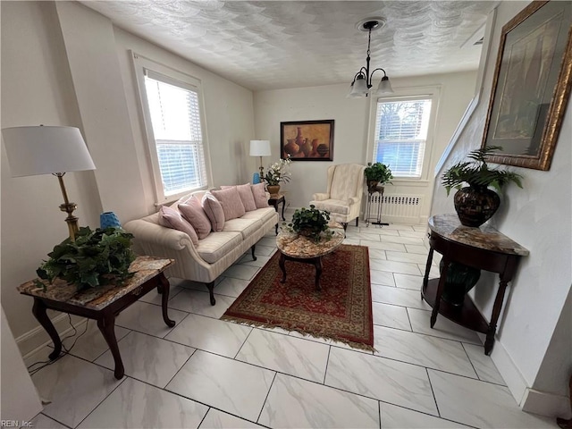 living room featuring marble finish floor, radiator, a textured ceiling, a chandelier, and baseboards