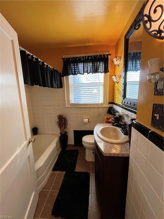 bathroom with toilet, plenty of natural light, tile walls, and tile patterned floors