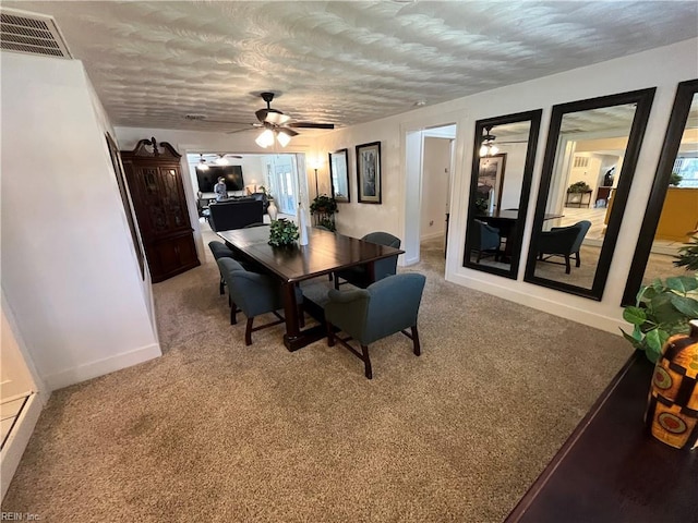 dining area featuring baseboards, visible vents, a ceiling fan, light colored carpet, and a textured ceiling