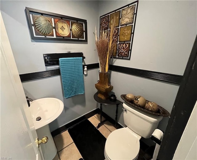 bathroom with tile patterned flooring, baseboards, and toilet