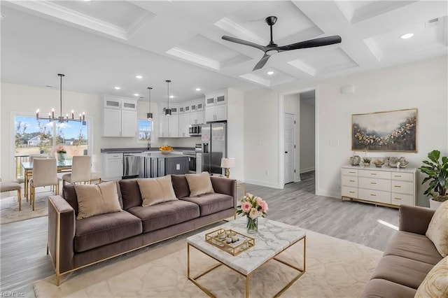 living area with light wood-style floors, baseboards, coffered ceiling, and ceiling fan with notable chandelier