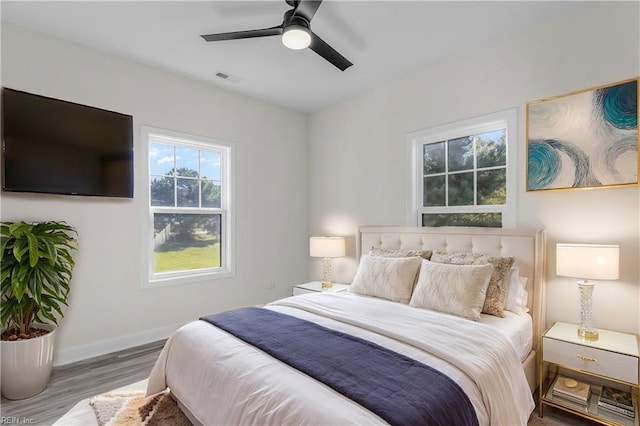 bedroom featuring visible vents, ceiling fan, baseboards, and wood finished floors