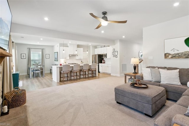 living area with recessed lighting, visible vents, light wood-style flooring, a ceiling fan, and baseboards