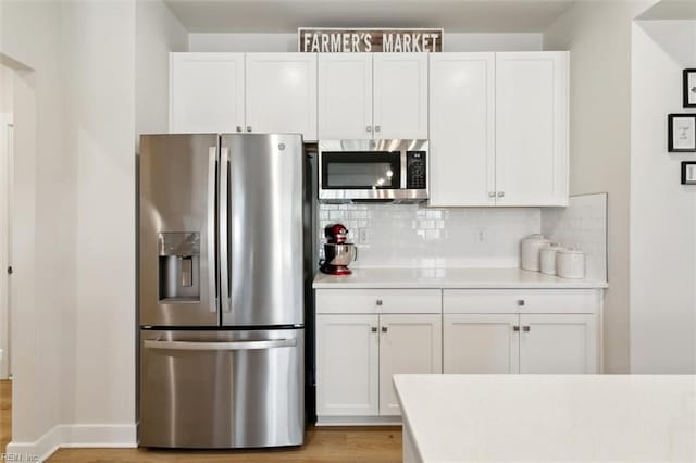 kitchen featuring white cabinets, light countertops, appliances with stainless steel finishes, light wood-type flooring, and tasteful backsplash