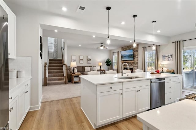 kitchen with a sink, visible vents, light countertops, stainless steel dishwasher, and an island with sink