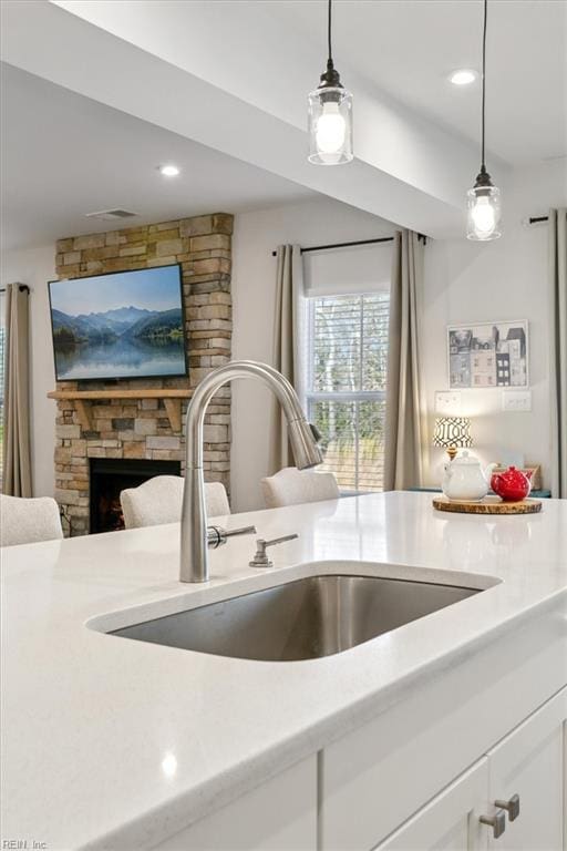 kitchen featuring light countertops, white cabinets, a sink, and hanging light fixtures