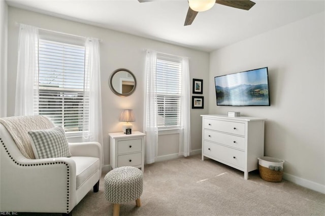 living area with light carpet, ceiling fan, and baseboards