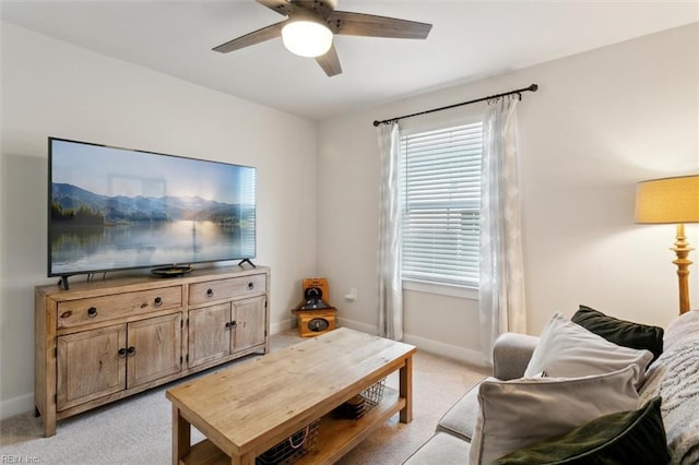 living area featuring baseboards, a ceiling fan, and light colored carpet