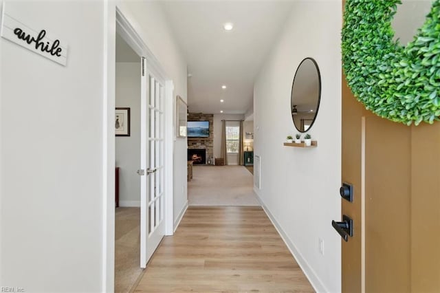 hallway with light wood-type flooring, recessed lighting, light carpet, and baseboards